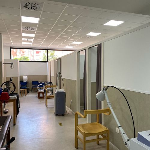 Imagen de sala alargada con aparatos de fisioterapia y electroterapia y puertas de acceso a otras salas a la derecha